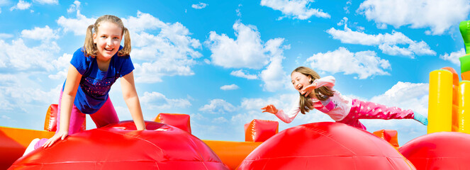 Two happy little girls having lots of fun while jumping from ball to ball on an inflate castle...