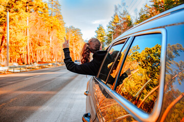 Pretty young brunette woman travelling by car late autumn on the mountains road