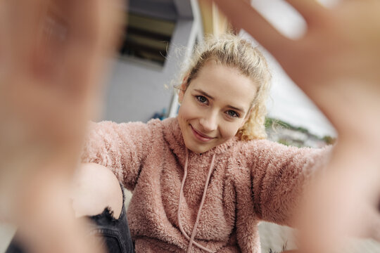 Young teenager looks through her hands into the camera