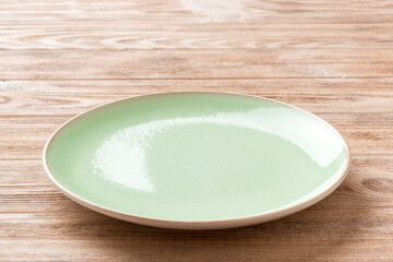 Perspective view of empty green plate on wooden background. Empty space for your design