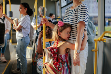 Sad schoolgirl embracing her mother in the city bus