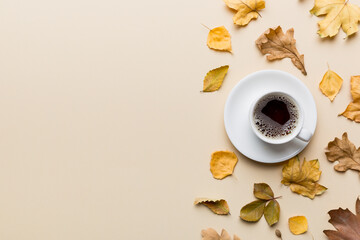 Flat lay composition with colorful Autumn cup of coffee and leaves on a color background. top view