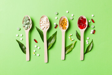 Top view Variety of vitamin and mineral pills in wooden spoon on Colored background. Top view of...