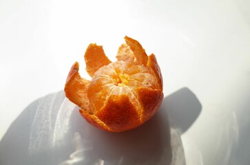Closeup of peeled mandarin orange on a white surface