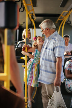 Grandfather with groceries and little girl in public transport