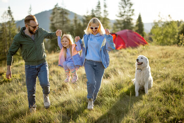 Young caucasian couple with little girl and dog have fun spending leisure time together while...