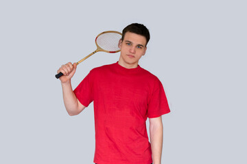 Portrait of an sad caucasian man holding a badminton racket on grey background