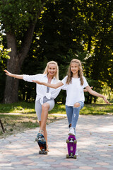 Obraz premium Mother and child daughter with skate and penny board in skate park. Extreme lifestyle. Family of mom and her kid spend time together.