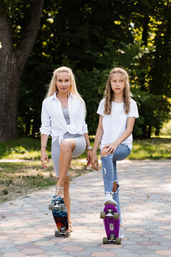 Mother and child daughter with skate and penny board in skate park. Extreme lifestyle. Family of mom and her kid spend time together.