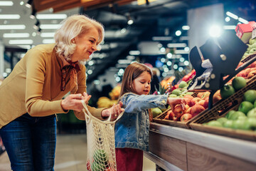 Senior woman shopping fruits with granddaughter