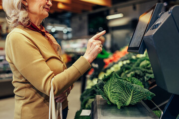 Woman in supermarket measuring vegetables