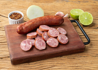 Calabrese pork sausage with slices over wooden board with seasonings
