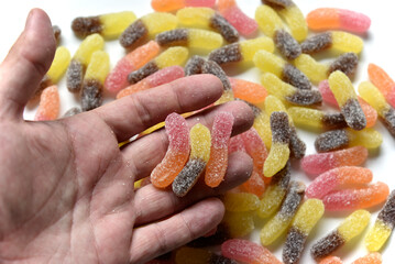 Sugar delicious marmalade worms in your hand on a white background