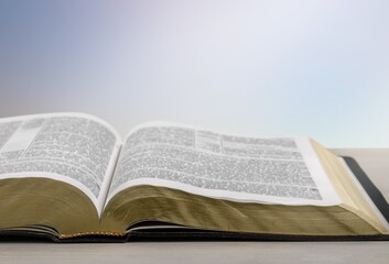 Open holy bible on a wooden table. Beautiful white wall background.