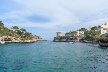 Fototapeta premium Coastal cliffs, boat and yacht in bay of Cala Figuera