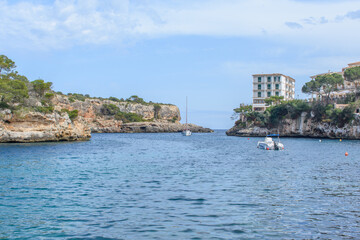Fototapeta na wymiar Coastal cliffs, boat and yacht in bay of Cala Figuera