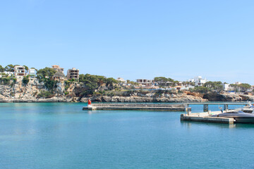 Fototapeta na wymiar Houses on top of the coastal cliffs in Porto Cristo. Calm, turquoise sea water