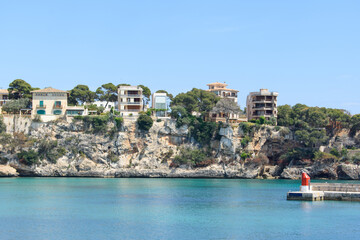 Fototapeta premium Houses on top of the coastal cliffs in Porto Cristo. Calm, turquoise sea water.