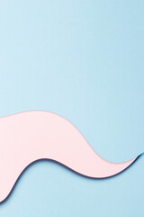 Abstract colored paper texture background. Minimal vertical composition with geometric shapes and curved lines in pastel pink and light blue colors. Top view