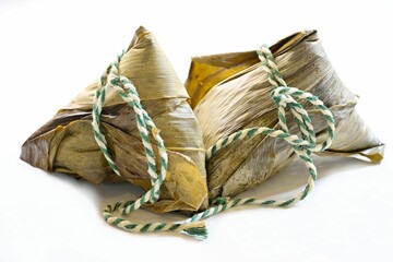 Two Chinese sticky rice dumplings, zongzi or bakcang, wrapped in bamboo leaves, on white background