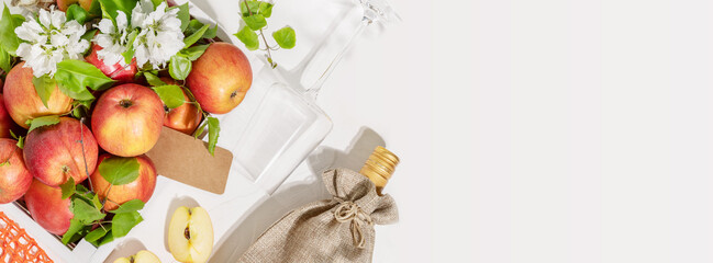 Farm apples in a white, wooden box, bottle of apple wine with glass on a white background with copy space. Summer, Low-alcohol, fruit drink. Fruit wine. Apple product. Soft focus style