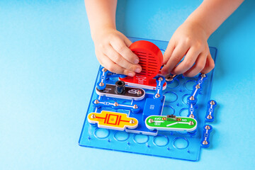 Kid's electronic constructor. Boy child development. Close up view of clever boy hands assembles a...
