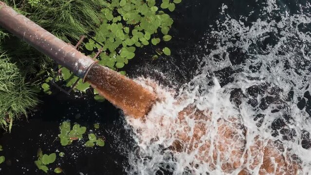 Dirty sewage is pouring from the pipe, industrial waste, man-made pollution of the environment.