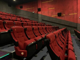 Empty interior of a cinema hall with rows of red chairs