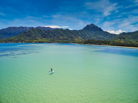 Aerial View Of A Paddle Boarder On Open Ocean Near Green Mountains On The Shore Of Oahu, Hawaii