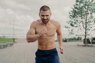 Athletic motivated male jogger takes part in running marathon, has aim to come first on finish, exercises outdoors and trains endurance. Active healthy sportsman has fitness training in morning.