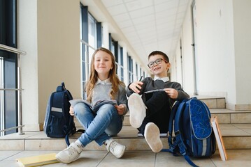 Portrait of smiling school kids in school corridor with books