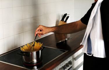 man cooking spaghetti at home in the kitchen