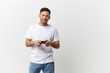 Happy smiling tanned handsome man in basic t-shirt enjoy favorite game with joystick gamepad posing...