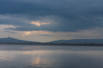 Fototapeta premium Upper water reservoir of the pumped storage hydro power plant Dlouhe Strane in Jeseniky Mountains, Czech Republic. Top of the Praded mountain behind the lake. During summer rainy morning, sunrise.