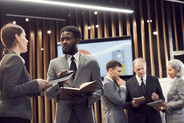Groups of multi-ethnic business people standing in modern conference room and exchanging ideas...