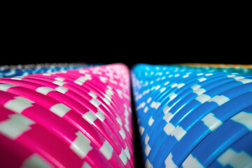 Vertical rows of colored casino chips on an isolated black background. Set of blue and pink...
