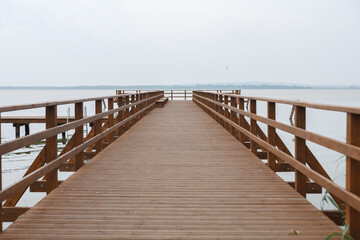 An empty, wide, wooden pier over the lake