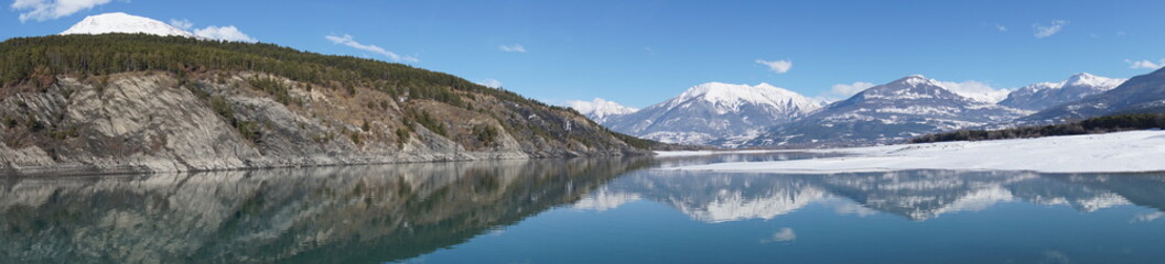 Fototapeta na wymiar panoramic view of serre ponçon lake in the mountains of the alps france with perfect mirror reflection in winter