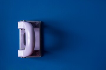 Top view of a small hole puncher on a blue background with copy space
