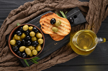 Black and green olives on a dark wooden black background.