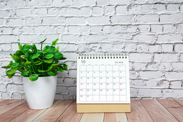 October 2022 white calendar with potted plant on wooden desk