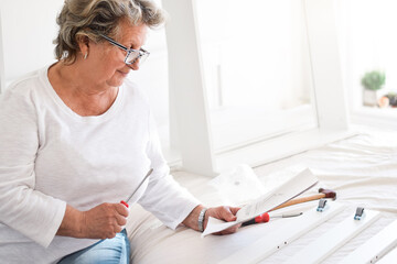 Senior woman reading a manual to assemble furniture