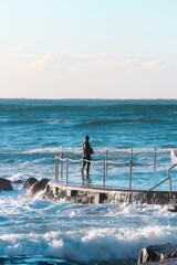 Man wearing diving suit and standing on a pier in the sea