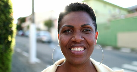 Beautiful African woman smiling at camera. Happy black ethnicity lady standing outdoors with...