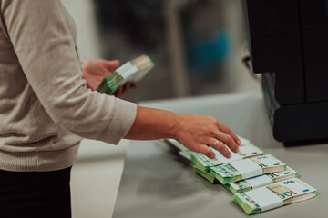 Bank employees holding a pile of paper banknotes while sorting and counting inside bank vault. Large amounts of money in the bank