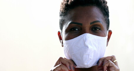 African woman putting covid face mask, black ethnicity female looking at camera