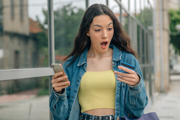 girl with mobile phone and credit card with expression of astonishment or surprise