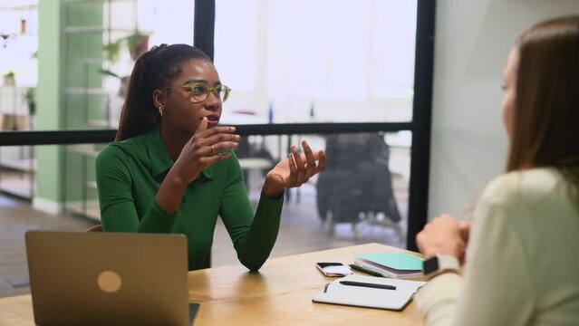 High-skilled female employee explaining something to coworkers during morning meeting, confident african-american businesswoman talking and gesturing, presenting her ideas