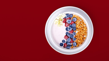 Smoothie bowls with granola, blueberries and raspberries on a red background. Healthy breakfast.