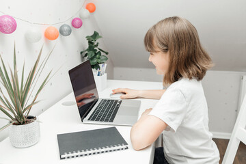 Distance learning at home. A schoolgirl girl does her homework on a laptop or watches a webinar online. Children and the Internet